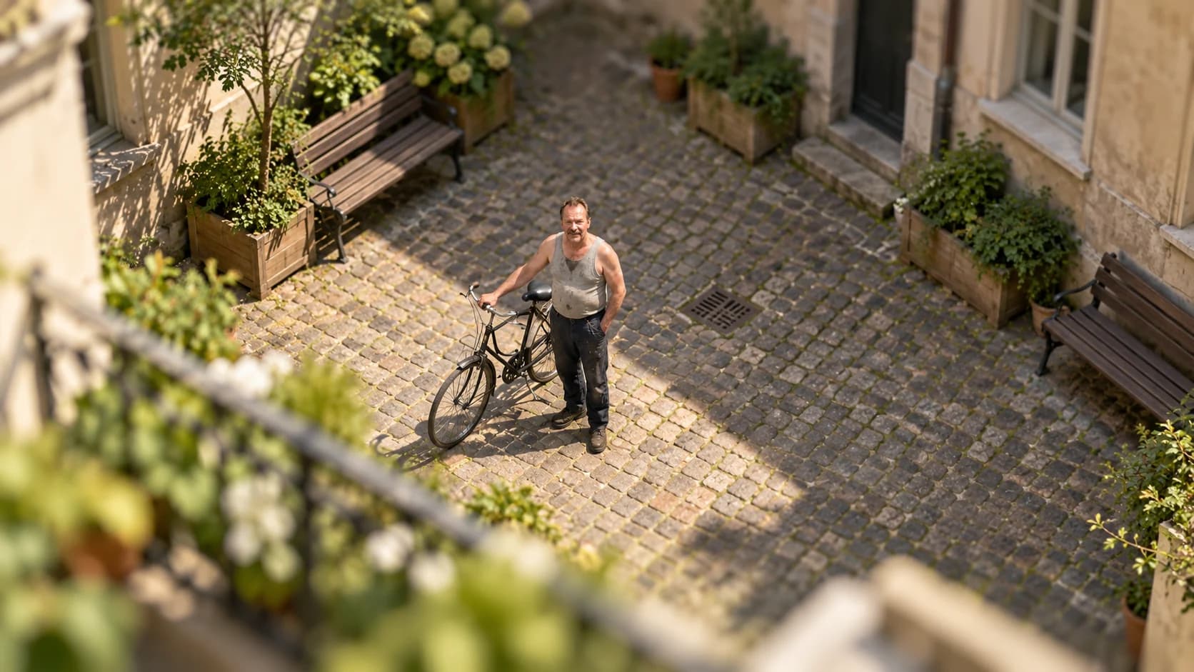 Brutalisti beside a bicycle in a courtyard viewed from above, with a narrow miniature-like band of focus.